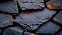 Dark slate stone pieces with rough textured surface and warm golden light highlighting natural cracks and layers, creating dramatic shadows and depth for luxury design background.