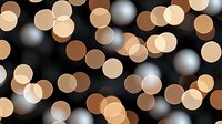 Glowing warm and cool bokeh lights create dreamy abstract background pattern with soft circular shapes on dark backdrop. Perfect for festive designs.