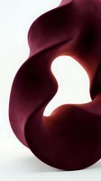 Abstract burgundy organic sculpture with flowing curves and smooth texture on white background, evoking nature and modern art concepts.