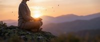 Young man meditating in lotus position on mountain rock during golden sunset with birds flying overhead, peaceful mindfulness practice in nature.