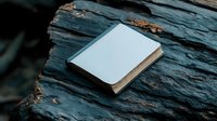 Blank white hardcover book mockup on dark stone background with natural texture. Minimalist design template for branding and product presentation.
