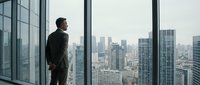 Business executive in suit standing by office window overlooking urban skyline, contemplating future opportunities and strategic planning decisions.