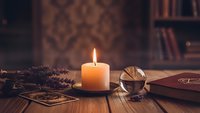 Cozy reading nook with burning candle, vintage books, and warm lighting creating atmospheric study space for relaxation and contemplation.
