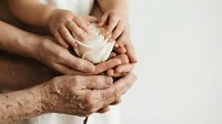 Three generations hands gently holding white paper heart together showing family love care support and unity concept for healthcare charity donation campaigns.