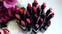 Assorted luxury lipsticks in pink and red shades arranged with roses, showcasing cosmetic products for beauty and makeup advertising and social media content.