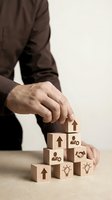 Businessman in suit building wooden blocks tower with business icons including arrows, people, handshake and lightbulbs representing growth strategy.