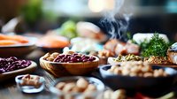 Variety of legumes and grains in wooden bowls on rustic table with steam rising, selective focus. Fresh herbs and ingredients create cozy kitchen atmosphere.