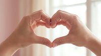 Hands forming heart shape gesture expressing love care and affection in soft natural lighting for romantic wellness concepts.