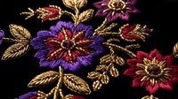 Luxurious embroidered floral pattern with vibrant purple, burgundy and gold thread flowers on black fabric. Ornate decorative textile design for fashion.