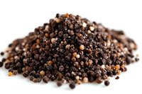Heap of mixed black, white and pink peppercorns on white background, macro food photography showing texture and details of whole dried spices.
