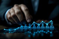 Glowing blue chess pieces aligned on ascending graph line showing business growth strategy while hand reaches to move piece, dark dramatic lighting.
