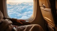 Passenger gazing at clouds through airplane window during flight, travel and journey concept for aviation, tourism, and wanderlust themes.