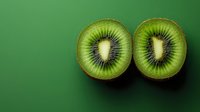 Fresh kiwi fruit halves showing vibrant green flesh and black seeds on matching green background for healthy eating and nutrition concepts.
