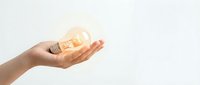 Hand holding glowing light bulb against white background symbolizing innovation, creativity, bright ideas and inspiration for business solutions.