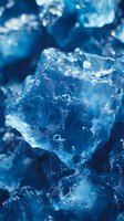 Macro shot of melting ice crystals with water droplets in deep blue tones creating abstract shapes and textures. Natural light enhances transparency and reflections.