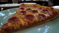 Appetizing pepperoni pizza slice on green plate showing melted cheese and crispy crust with rich tomato sauce, classic Italian cuisine close-up view.