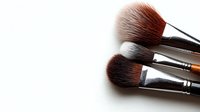 Professional makeup brushes with soft brown and black bristles arranged diagonally on white background, isolated with copy space for beauty and cosmetic industry use.