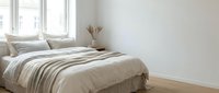 Cozy bedroom with striped bedding, neutral tones, and natural light from windows, perfect for home decor and interior design projects.