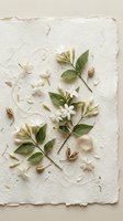White jasmine branches with green leaves, buds, and scattered petals arranged on textured handmade paper, evoking natural elegance for wedding and botanical designs.