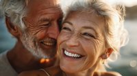 Joyful senior couple laughing together outdoors in warm golden sunlight, showing genuine happiness and love in their retirement years.