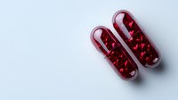 Red transparent capsules filled with heart-shaped pills on white background, medical and healthcare concept for pharmacy, wellness and treatment.