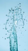 Clear water splash with droplets and bubbles rising upward against light blue background for refreshment and hydration concepts.