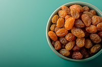 Sweet dried raisins in ceramic bowl on turquoise background with copy space. Healthy natural snack and ingredient for cooking and baking.