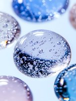 Macro shot of glass spheres with air bubbles inside on light background, artistic close-up showing transparent texture and reflections in blue tones.