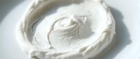 Creamy white whipped dairy topping swirled in bowl, ready for dessert decoration, baking, and culinary applications.