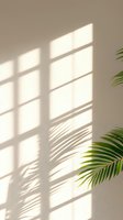 Window light casting geometric shadows on beige wall with palm leaf creating organic shadow patterns, minimal contemporary interior design aesthetic.