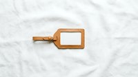 Brown leather luggage tag with blank white label on marble surface for travel identification and personalization.
