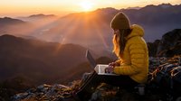 Golden hour mountain landscape with woman in yellow jacket working on laptop at sunrise, remote work and digital nomad lifestyle concept.