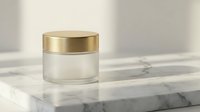 Luxury glass cosmetic jar with golden cap on marble surface for premium skincare product packaging and beauty brand presentation.
