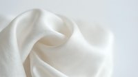 Soft white fabric with delicate folds and flowing waves, isolated on light background. Suitable for textile, fashion, and design projects.