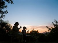 Silhouettes of adult and child enjoying sunset together outdoors among trees and foliage, perfect for family, parenting, nature and lifestyle concepts.