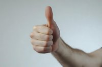 Caucasian male hand giving thumbs up gesture against neutral background, expressing approval, success, and positive feedback for business, marketing, and motivational content.