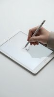 Hand holding stylus pen drawing on white tablet screen for digital art creation and graphic design work.