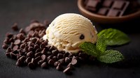 Creamy vanilla ice cream scoop with scattered dark chocolate chips and fresh mint leaves on black background, dramatic lighting creates appetizing dessert composition.