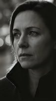 Dramatic black and white portrait of contemplative middle-aged Caucasian woman with intense gaze and emotional expression in moody lighting.