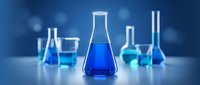 Laboratory glassware with blue chemical solutions on white surface against blue background for scientific research and education.