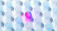 Bright pink light bulb glowing among blue transparent bulbs on white background. Creative innovation concept for business solutions and unique ideas.