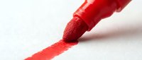 Red marker drawing a line on white paper, suitable for education, art projects, creativity concepts, and design work.