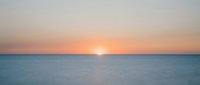 Serene ocean horizon at sunrise with golden sun reflecting on calm water, peaceful seascape for relaxation and wellness projects.