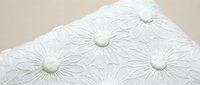 White embossed floral pattern on textured paper surface with raised daisy motifs for elegant stationery and craft projects.