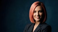 Professional businesswoman with pink bob haircut smiling confidently in dark suit against navy background for corporate headshots and business presentations.