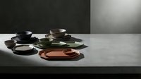 Modern ceramic dinnerware set with colorful plates and cups arranged on minimalist table for contemporary kitchen and dining room decor.
