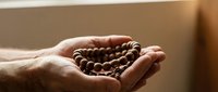 Cupped hands holding fresh roasted coffee beans in warm natural light for brewing and cafe concepts.