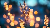 Delicate grass silhouette against blurred golden bokeh lights and dreamy blue background creates magical evening atmosphere. Nature meets light photography.