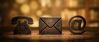 Wooden contact icons phone envelope email symbol on rustic table with warm bokeh background for business communication and customer service concepts.