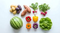 Fresh organic vegetables and fruits arranged on white background including watermelon, potatoes, sweet potatoes, radishes, lettuce, bell peppers for healthy eating.